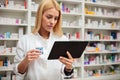 Serious young female pharmacist using a tablet in a drugstore