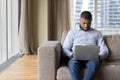 Serious young freelance businessman typing on laptop, sitting on sofa Royalty Free Stock Photo