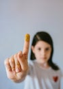 Serious young girl looking at camera while showing her finger covered of golden glitter