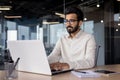 Serious young Indian businessman man working focused on laptop while sitting in office at desk Royalty Free Stock Photo