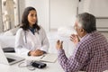 Serious young Latin doctor woman meeting with senior Indian patient Royalty Free Stock Photo