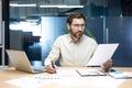 Serious young male analyst and accountant sitting in the office at his desk, working with documents, recording and checking data Royalty Free Stock Photo