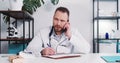 Serious young male Caucasian doctor consulting remote patient on self isolation talking on the phone at modern office. Royalty Free Stock Photo