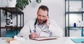 Serious young male Caucasian doctor consulting remote patient on self isolation talking on the phone at modern office. Royalty Free Stock Photo