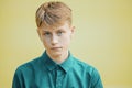 Serious young man in a blue shirt on a yellow background Royalty Free Stock Photo