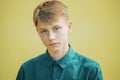 Serious young man in a blue shirt on a yellow background Royalty Free Stock Photo