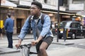 Serious young man in a denim jacket and short shorts riding a bicycle on the street