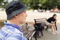 A serious young man on a park bench with a girl in the background. A man is sitting in a city park and looking into the distance.A Royalty Free Stock Photo