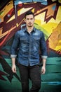 Serious young man standing against colorful graffiti wall