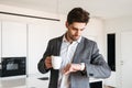 Serious young man in suit looking at his wrist watch Royalty Free Stock Photo