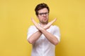 Serious young man in white shirt and glasses showing stop sign and looking at camera Royalty Free Stock Photo