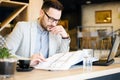 Young architect looking at building blueprints. working in a cafe Royalty Free Stock Photo