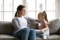 Serious mother talk with small daughter in living room