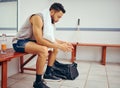 Serious young player sitting in a locker room. Mixed race man waiting in a gym locker room. Young man taking a break Royalty Free Stock Photo