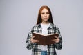 Serious young woman college student holding opened books and looking at camera on gray background. Royalty Free Stock Photo