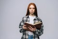 Serious young woman college student holding opened books and looking at camera on gray background. Royalty Free Stock Photo