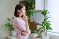 Serious young woman looking out the window, in home interior Royalty Free Stock Photo