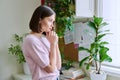 Serious young woman looking out the window, in home interior Royalty Free Stock Photo