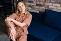 Serious young woman sitting in a comfortable chair in dark living room, looking at the camera. Royalty Free Stock Photo