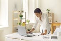 Serious concentrated woman standing at desk in home office and working on laptop computer Royalty Free Stock Photo