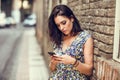 Serious young woman using her smart phone outdoors. Royalty Free Stock Photo