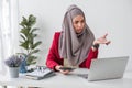 Serious young woman wearing hijab sitting at desk working on new business project alone in modern office Royalty Free Stock Photo