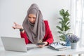 Serious young woman wearing hijab sitting at desk working on new business project alone in modern office Royalty Free Stock Photo