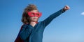 Seriuos child wearing a superhero costume. Super hero child against blue summer sky background. Kid having fun outdoors Royalty Free Stock Photo