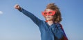 Seriuos child wearing a superhero costume. Super hero child against blue summer sky background. Kid having fun outdoors Royalty Free Stock Photo