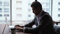 Serous concentrated young businessman doctor is working typing on modern laptop computer