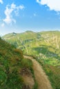 A serpentine track road narrow path at mountainside going up around a top of a hill and a beautiful panoramic view of a chain Royalty Free Stock Photo