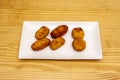 Serrano ham croquettes portion fried in olive oil on a white porcelain tray served