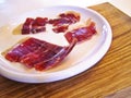 Serrano ham slices in white plate on wooden board Royalty Free Stock Photo