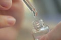 Serum dripping from a pipette into a bottle close-upin female hands . A drop of care product dripping into a bottle