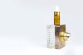 Serum in glass bottle with pipette and perfume spray bottle. Layout stack of two unbranded cosmetic bottles on white background.