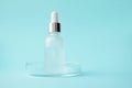 Serum in glass bottle with pipette in petri dish on blue background and copy space. Facial, eye, body or hair care beauty product