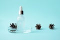 Serum in glass bottle with pipette in petri dish and pine cone on blue background and copy space. Concept skincare dermatology