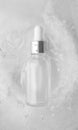 Serum in glass bottle with water drops in ice background, vertical. Concept summertime beauty product, top view. Cooling summer