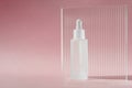 Serum oil with collagen and peptide in white transparent bottle with dropper on pink backdrop with acrylic ribbed sheet