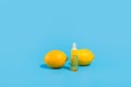 Serum in a transparent bottle with a pipette with yellow lemons on blue background. Royalty Free Stock Photo