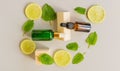 Serum with vitamin C. Lemon essential oil. Brown and green glass bottle with a pipette, slices of lemon with mint leaves on a gray Royalty Free Stock Photo