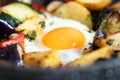 Serve one fried egg with baked vegetables, sausage. Round bright yellow yolk in the center