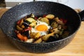 Serve one fried egg with baked vegetables, sausage. Round bright yellow yolk in the center