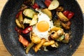 Serve one fried egg with baked vegetables, sausage. Round bright yellow yolk in the center