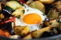 Serve one fried egg with baked vegetables, sausage. Round bright yellow yolk in the center