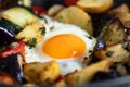 Serve one fried egg with baked vegetables, sausage. Round bright yellow yolk in the center