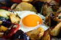 Serve one fried egg with baked vegetables, sausage. Round bright yellow yolk in the center