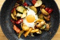 Serve one fried egg with baked vegetables, sausage. Round bright yellow yolk in the center