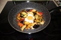 Serve one fried egg with baked vegetables, sausage. Round bright yellow yolk in the center