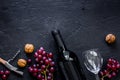 Serve wine. Bottle, glass, nuts and grape on black table background top view copyspace